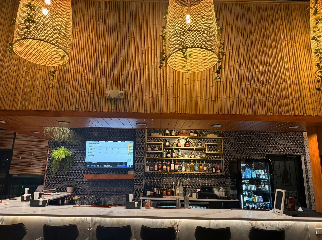 The Thai Zen bar with a marble countertop, dark patterned wall and bamboo pendant lights.