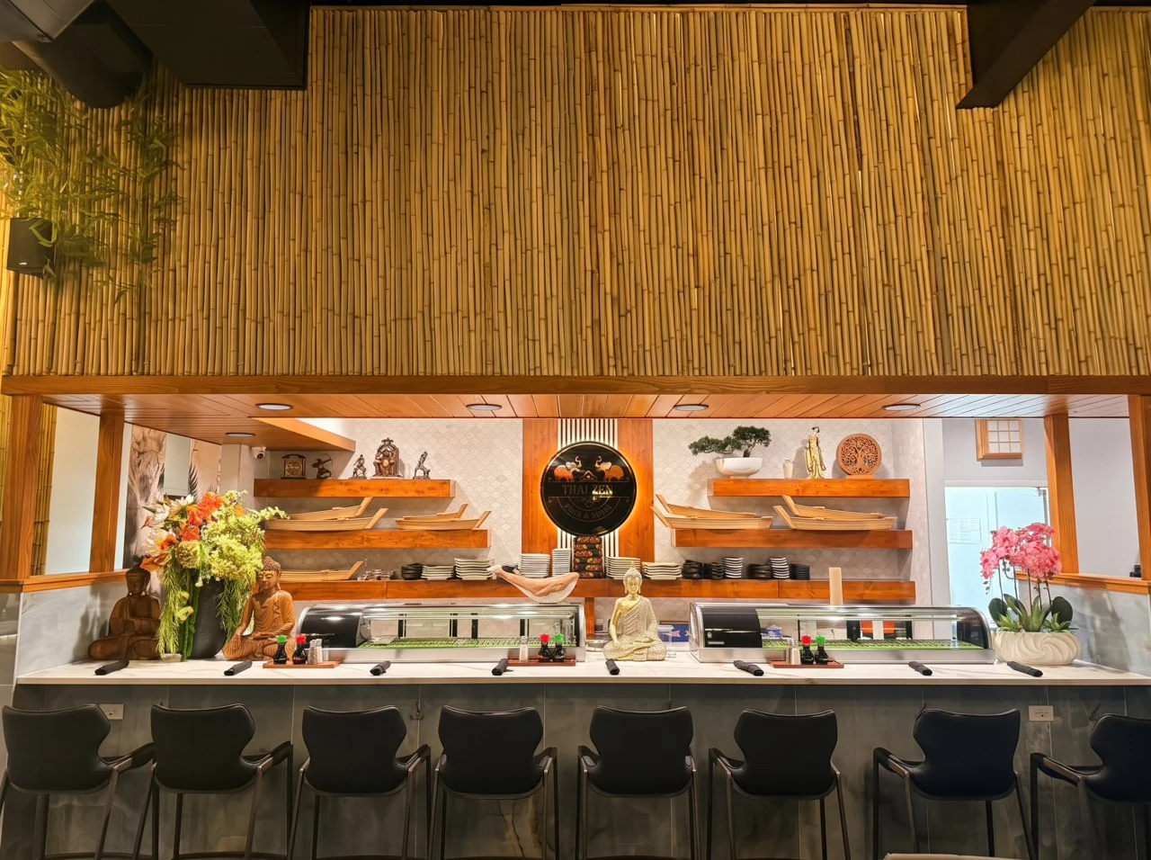 Thai Zen sushi counter with marble surfaces, black bar stools and the original gold restaurant emblem.